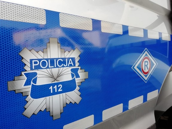 logotyp policyjnej gwiazdy oraz symbol Wydziału Ruchu Drogowego na niebieskim tle drzwi radiowozu