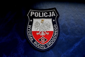 Naszywka z orłem na biało czerwonym tle i logotypem policjantów ruchu drogowego, w górnej części napis „policja”, wokół obrzeży napis „wydział ruchu drogowego”