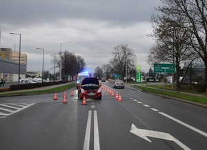 Uszkodzenia powypadkowe przedniej części suzuki. Podniesiona pokrywa silnika, w tle policyjny radiowóz