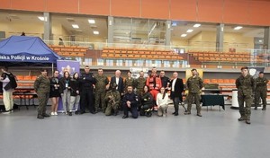 Policjanci z żołnierzami oraz przedstawicielami uczelni w Sanoku na pamiątkowej fotografii w czasie „Dnia otwartego”. Obok policyjny namiot profilaktyczny