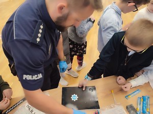 Policjant podczas pobierania odcisków palców od uczestnika spotkania