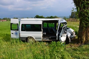 Znajdujący się poza drogą bus. Przednia część pojazdu zniszczona po zderzeniu z drzewem