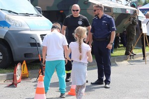 Policjanci podczas festyny podczas prezentacji wyposażenia na stoisku ekspozycyjnym