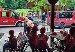 Policjantka podczas pokazu pierwszej pomocy, na pierwszym palnie młodzi uczestnicy szkolenia