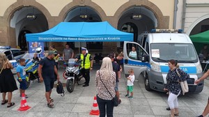 mieszkańcy odwiedzający policyjne stoisko wystawiennicze. W tle policyjny radiowóz i motocykle