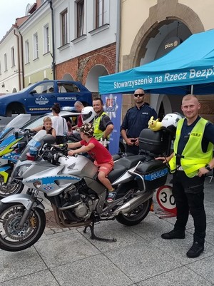 Mieszkańcy odwiedzający policyjne stoisko wystawiennicze. Na zdjęciu funkcjonariusze prezentujący motocykle służbowe