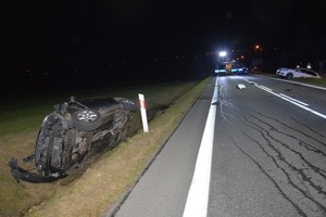 Uszkodzenia powypadkowe znajdującego się w przydrożnym rowie nissana. W tle pojazdy służb ratowniczych