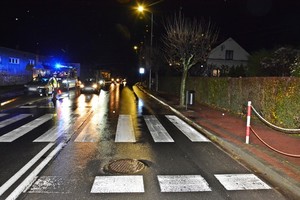 Na pierwszym planie przejście dla pieszych, w tle policjant regulujący ruchem i radiowóz z włączonymi światłami błyskowymi