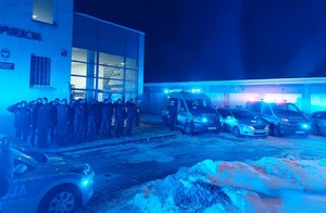 Policjanci oddają hołd poległym kolegom. W tle radiowozy z włączonymi sygnałami świetlnymi