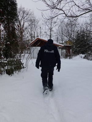 policjant brodzący w śniegu podczas kontroli opuszczonej altany