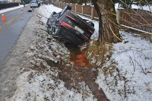 Przewrócone na dach audi w przydrożnym rowie. W tle policyjny radiowóz