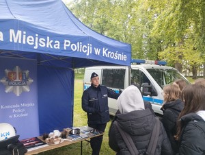 policjant pod namiotem profilaktycznym podczas pikniku mundurowego w rozmowie z młodzieżą