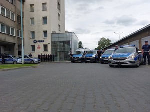 Policjanci przy radiowozach podczas oddawania hołdu poległemu żołnierzowi