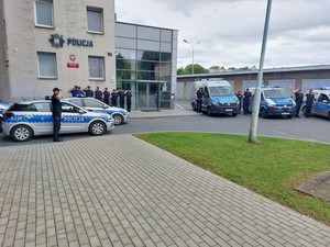 Policjanci przy radiowozach podczas oddawania hołdu poległemu żołnierzowi