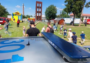 uczestnicy pikniku rodzinnego, na pierwszym planie górna część radiowozu