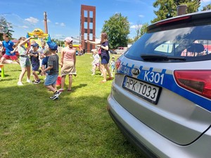 uczestnicy pikniku rodzinnego, na pierwszym planie tylna część radiowozu