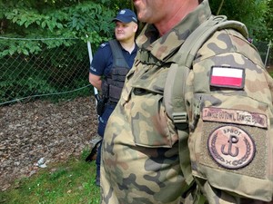 zdjęcie żołnierza w mundurze, w tle policjant