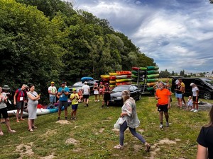 uczestnicy spływu na placu przed rozpoczęciem zawodów,w tle ułożone na lawecie kajaki