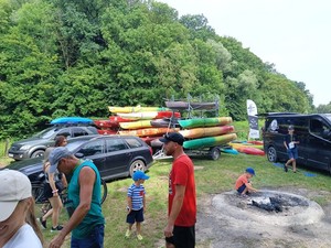 uczestnicy spływu na placu przed rozpoczęciem zawodów,w tle ułożone na lawecie kajaki