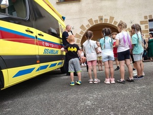 policjant na tle karetki pogotowia podczas rozmowy z dziećmi uczestniczącymi w pikniku rodzinnym