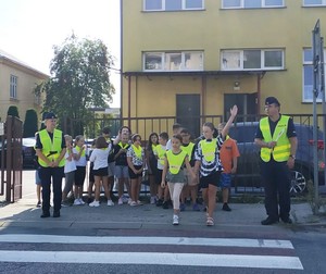 policjanci na przejściu dla pieszych z uczniami podczas działań Bezpieczna droga do szkoły