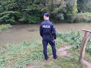 policjant monitorujący poziom wody w związku z zagrożeniem powodziowym