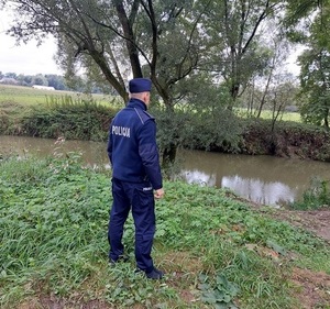 policjant monitorujący poziom wody w związku z zagrożeniem powodziowym