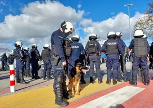 policjant z psem służbowym, w tle inni funkcjonariusze biorący udział w zabezpieczeniu