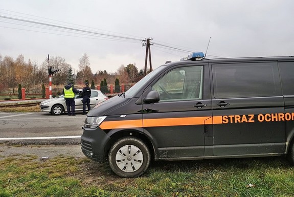 pojazd straży ochrony kolei, w tle funkcjonariusze kontrolujący samochód