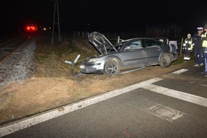 służby pracujące na miejscu zdarzenia, na pierwszym planie uszkodzony samochód