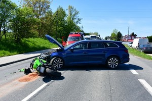 uszkodzenia pokolizyjne motocykla i samochodu osobowego. W tle pojazd służb ratowniczych oraz inni uczestnicy ruchu