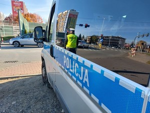 policyjny radiowóz i stojący obok niego funkcjonariusz ruchu drogowego