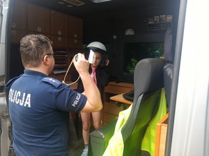 dziewczynka podczas odwiedzania radiowozu, na pierwszym planie stojący tyłem policjant