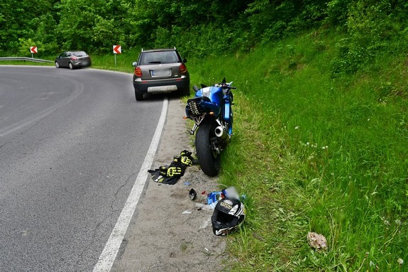 Miejsce wypadku drogowego. Na pierwszym planie motocykl i znajdujący się za nim samochód osobowy