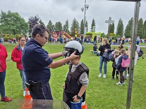 Stoisko profilaktyczne podczas obchodów Dnia Dziecka w Miejscu Piastowym. Na zdjęciu policjant oraz uczestnicy festynu