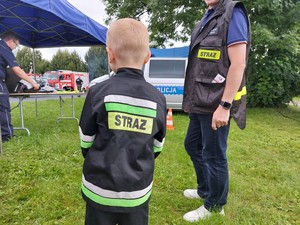 chłopiec w strażackim uniformie podczas odwiedzin policyjnego namiotu profilaktyki