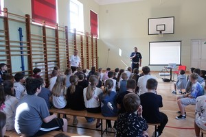 uczniowie podczas spotkania na hali sportowej z policjantem ruchu drogowego