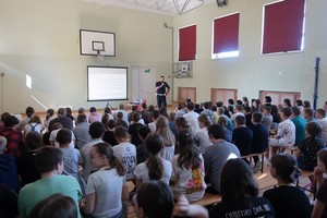uczniowie podczas spotkania na hali sportowej z policjantem ruchu drogowego