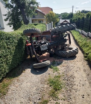 przewrócony na bok ciągnik rolniczy na drodze dojazdowej do domu