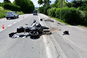 leżący na jezdni motocykl z uszkodzeniami powypadkowymi, w tle samochody