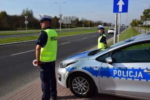 policjanci ruchu drogowego stojący przy radiowozie