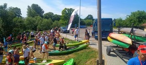 uczestnicy spływu kajakowego wraz ze sprzętem na brzegu rzeki przed startem