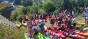 uczestnicy spływu kajakowego wraz ze sprzętem na brzegu rzeki przed startem