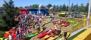 uczestnicy spływu kajakowego wraz ze sprzętem na brzegu rzeki przed startem