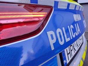 tylna część radiowozu z napisem policja na niebieskim pasie pokrywy bagażnika
