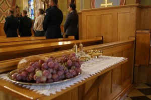 Uczestnicy uroczystych obchodów Święta Policji podczas nabożeństwa w kościele. Na pierwszym planie chleb i winogrono