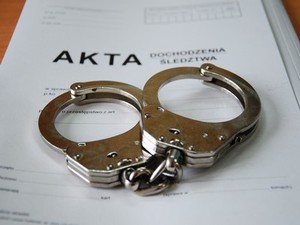 Zdjęcie teczki z napisem "AKTA" oraz kajdanek