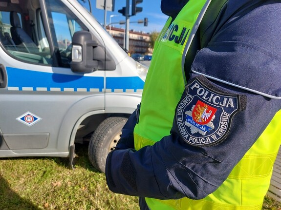 W tle widoczny radiowóz oraz policjant